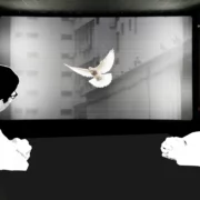 Due frati guardano uno schermo dove vola una colomba